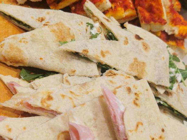 Assortimento di focacce, pizza e piadine farcite su un tagliere di legno.