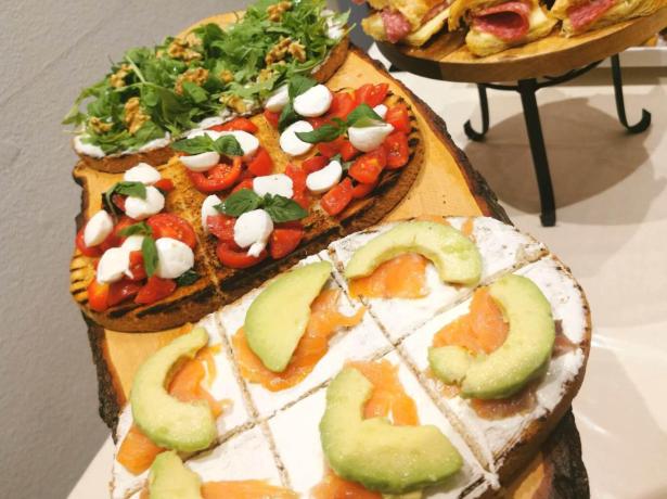Variety of bruschetta and stuffed croissants on wooden boards.